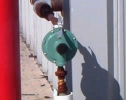 Second stage propane gas regulator installed alongside a building